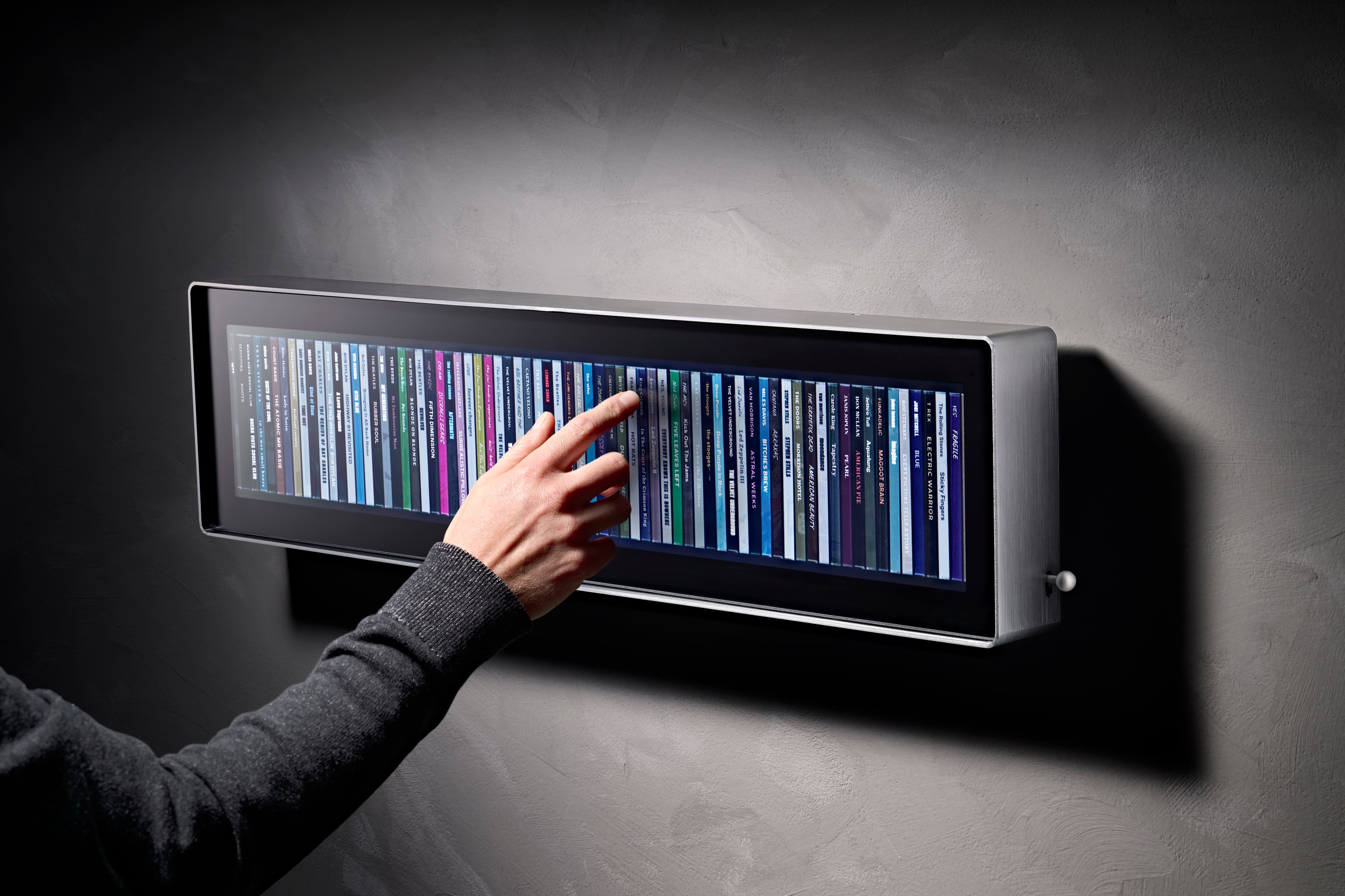A hand reaching in to touch an album spine on the Spine display